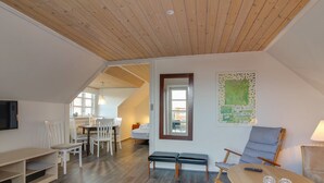 A spacious room with a wooden ceiling, a dining area with white chairs, a bench, and a table with two glasses. - "Gæsling" - 1.6km from the sea by Interhome (Skagen)