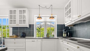 Cocina moderna con armarios blancos, encimera negra y ventana con vistas al verdor.