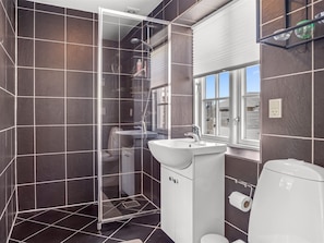 A modern bathroom with a glass shower enclosure, a white sink, and a toilet.