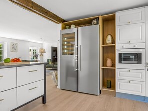 Une cuisine équipée d’un réfrigérateur à deux portes, de meubles de rangement en bois et d’un four encastré.