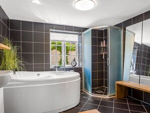 Ein modernes Badezimmer mit einer freistehenden Badewanne, einer Duschkabine und einem großen Spiegel.