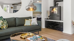 Una sala de estar moderna con sofá, una mesita redonda, chimenea y un espejo en la pared.