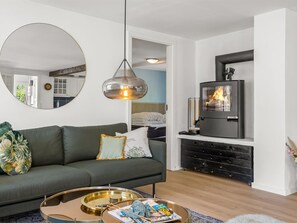 Ein modernes Wohnzimmer mit einer Couch, einem runden Couchtisch, einem Kamin und einem Spiegel.