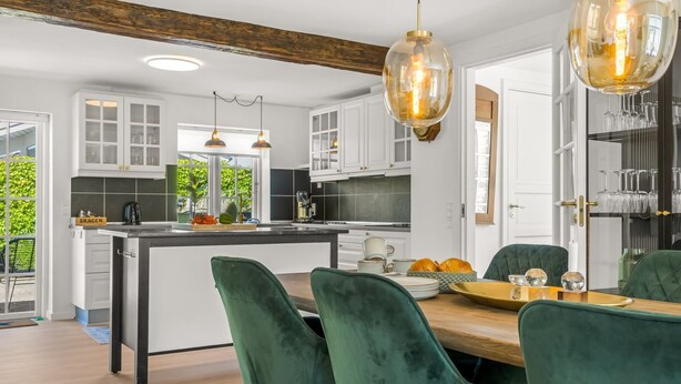 Una cocina moderna con armarios blancos, una isla central e iluminación colgante.