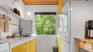 Een moderne keuken met gele kastjes, een raam met uitzicht op groen, en een koffiezetapparaat op het aanrecht.