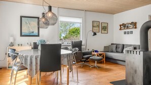 Een moderne woonkamer met een eetgedeelte, voorzien van een open haard, een bank en een eettafel met stoelen.