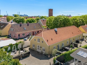Ein Innenhof mit traditioneller europäischer Architektur, einem offenen zentralen Bereich und einem Blick auf Industriegebäude in der Ferne.