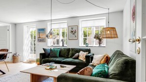 A living room with a green sofa, a coffee table, and a hanging lamp. - "Viivi" - 900m from the sea by Interhome (Skagen)