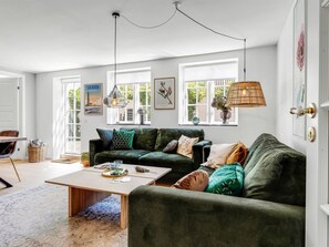 Ein modernes Wohnzimmer mit einem grünen Sofa, einem Holztisch und einer Pendelleuchte.