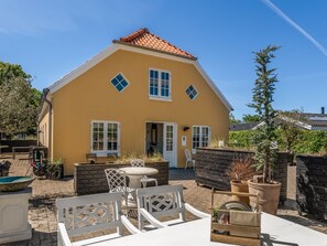 A yellow building with a tiled roof, white-framed windows, and a door.