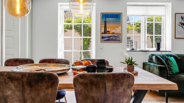 A dining area with a wooden table, chairs, and pendant lights. - "Viivi" - 900m from the sea by Interhome (Skagen)