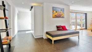A modern living room with a sofa, a painting, and a bookshelf.