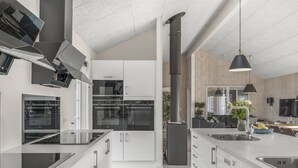 Una cocina moderna con electrodomésticos de acero inoxidable, una isla central con fregadero y un amplio ventanal que proporciona luz natural.