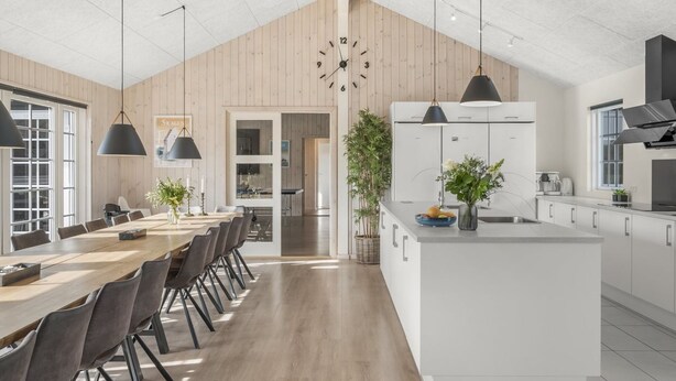 Una cocina moderna con una isla central, armarios blancos e iluminación colgante.