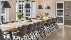 Un comedor amplio con una larga mesa de madera, varias sillas y lámparas colgantes.