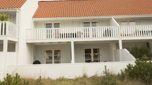 Een gebouw met twee verdiepingen, een rood pannendak, witte buitenmuren en een balkon met witte leuningen.
