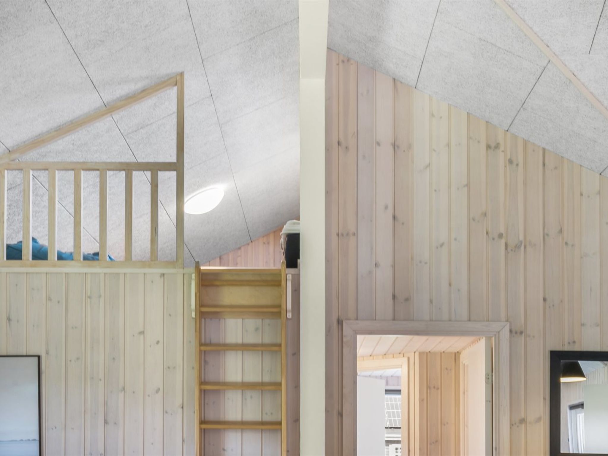 A room with wooden panel walls, a sloped ceiling, and a built-in wooden ladder.