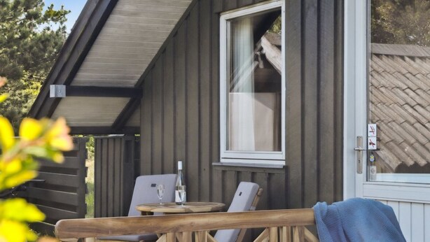 Un pontile in legno con tavolo e sedie, una finestra che mostra l'interno e una porta con una finestra.
