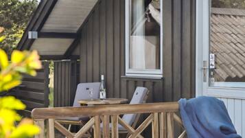 Eine Holzdiele mit Tisch und Stühlen, ein Fenster mit Blick ins Innere und eine Tür mit Fenster.