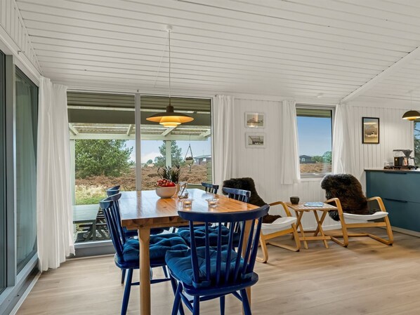 A dining area with a wooden table, blue upholstered chairs, and pendant lighting.