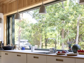 Une cuisine dotée d’une grande fenêtre, d’un évier et de divers ustensiles de cuisine disposés sur le plan de travail.