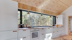 Une cuisine moderne avec une grande fenêtre, un plafond en bois et un tapis à rayures.