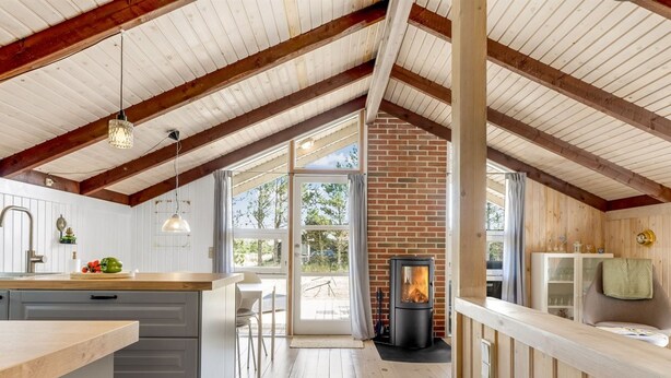 Une cuisine moderne avec un plafond en bois, une cheminée et une vue sur l’extérieur.