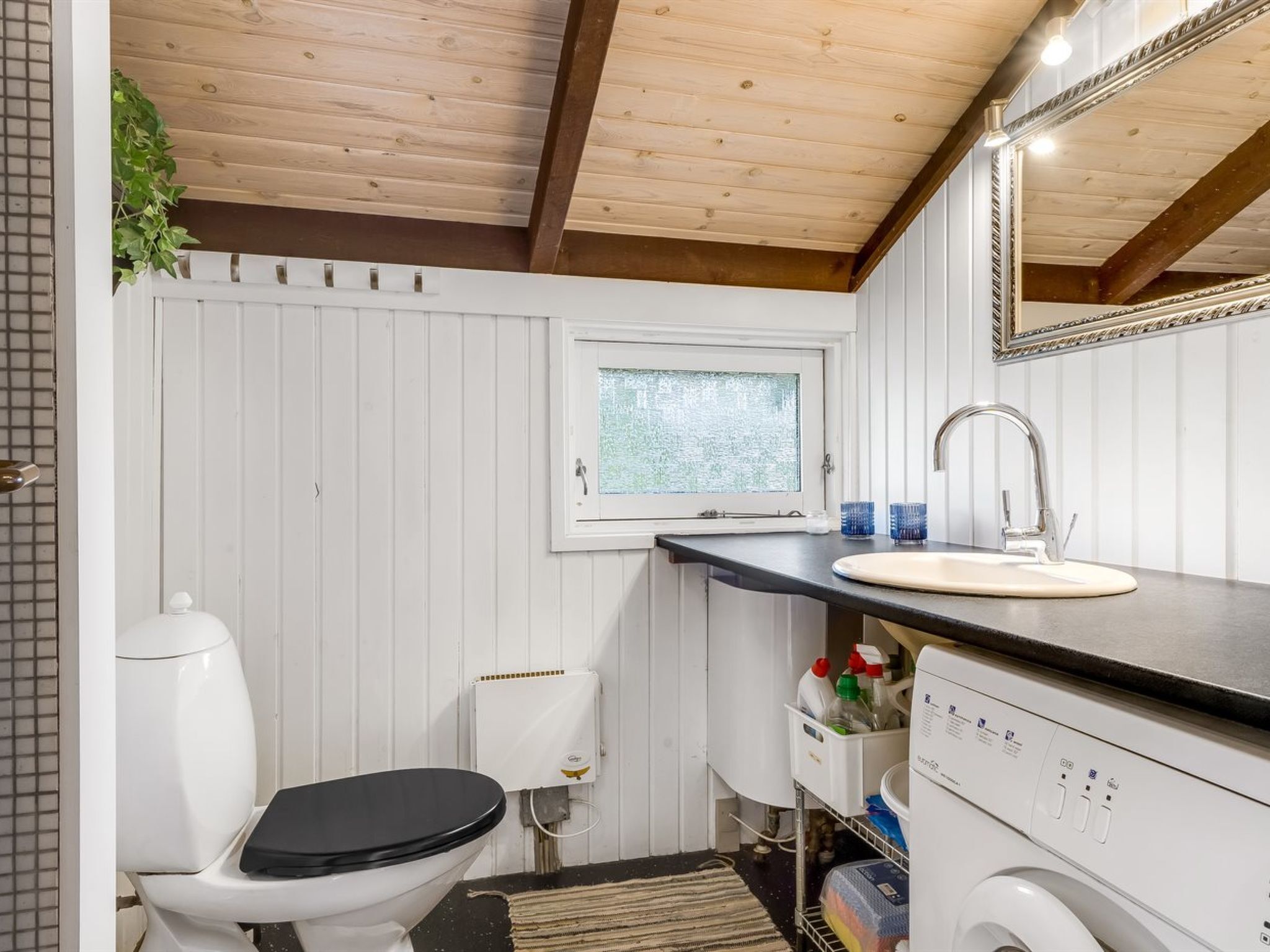 A compact bathroom with a toilet, sink, and a small window.