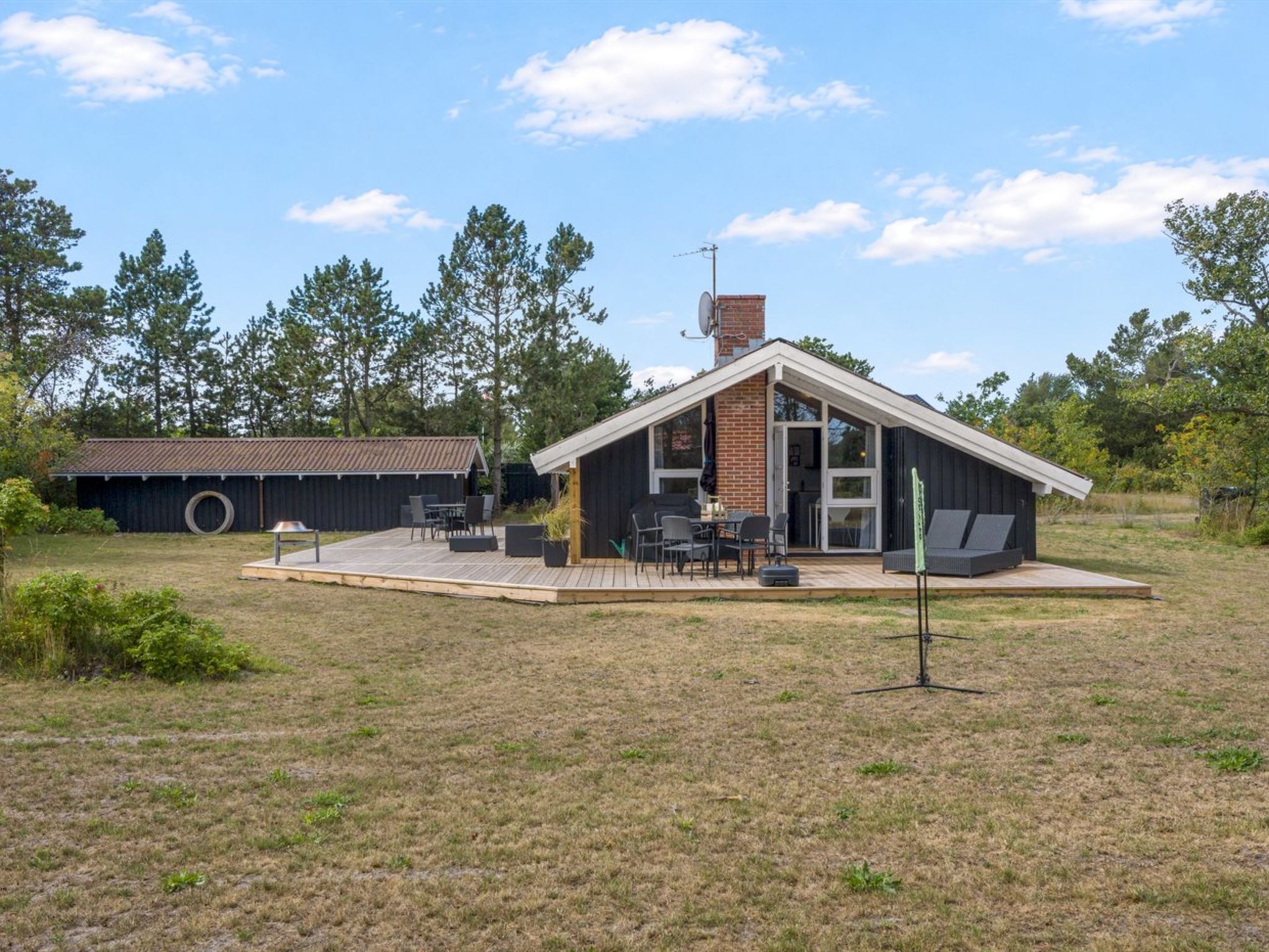 Una casa moderna con un patio, una zona de estar cubierta al aire libre y una antena parabólica.