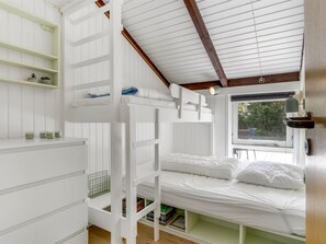 A bunk bed room with a window, a desk, and shelves.