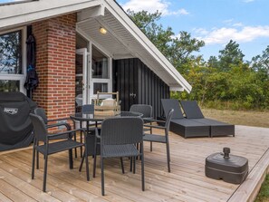 An outdoor deck with a grill, wicker furniture, and a view of the house.