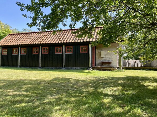 Un bâtiment avec un toit en tuiles, une façade en bois et un banc à l’extérieur.