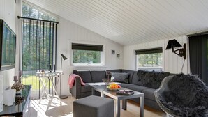 Een moderne woonkamer met een grijze bank, een ronde zwarte stoel en een klein tafeltje met fruit.