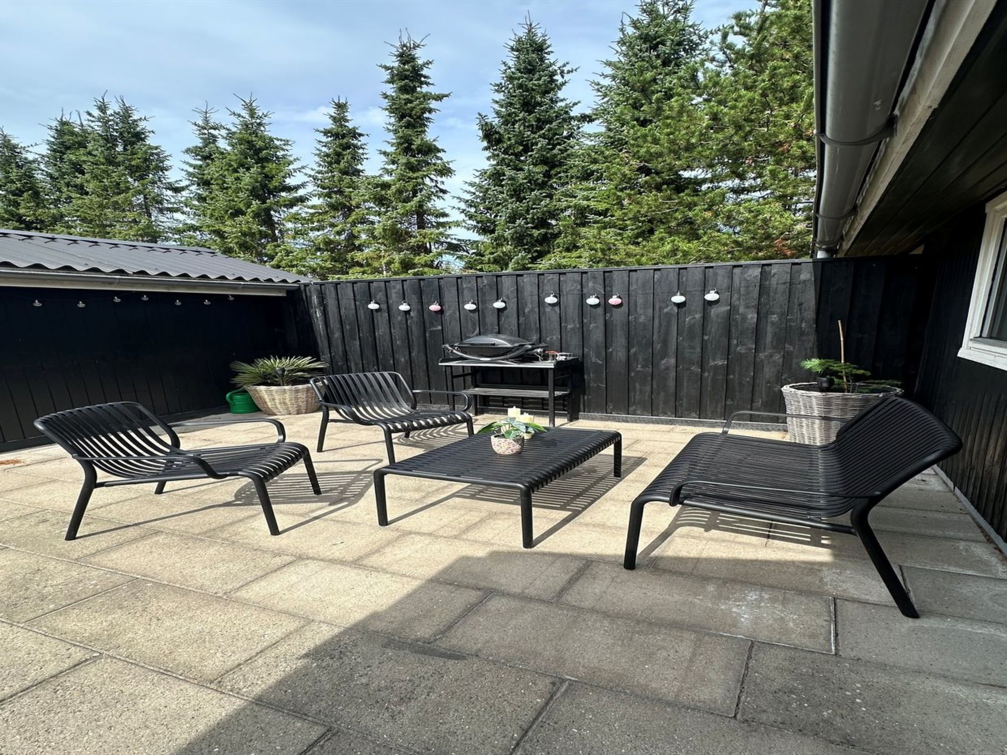 Eine Terrasse mit Gartenmöbeln und einem Grill.
