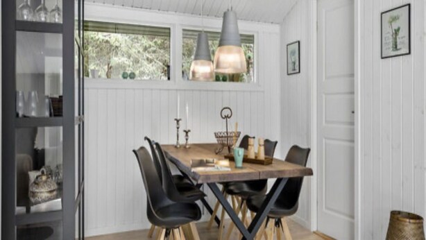 Een eetruimte met een houten tafel, zwarte stoelen en hanglampen.