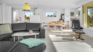 A modern living room with a black sofa, a round coffee table, and a dining area with a table and chairs. - "Ehm" - 600m from the sea by Interhome (Strandby)