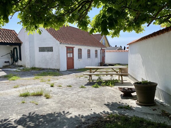 A courtyard with a white building, a red door, and a picnic table.