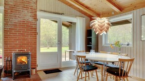 A cozy room with a brick fireplace, wooden ceiling, and a dining area with a table and chairs. - "Thorger" - 5km from the sea by Interhome (Læsø)