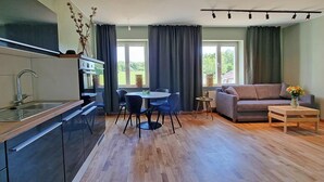 A modern kitchen with a dining area, a sofa, and a small table with a vase of flowers. - Sankt Anna Resort (Sankt Anna)