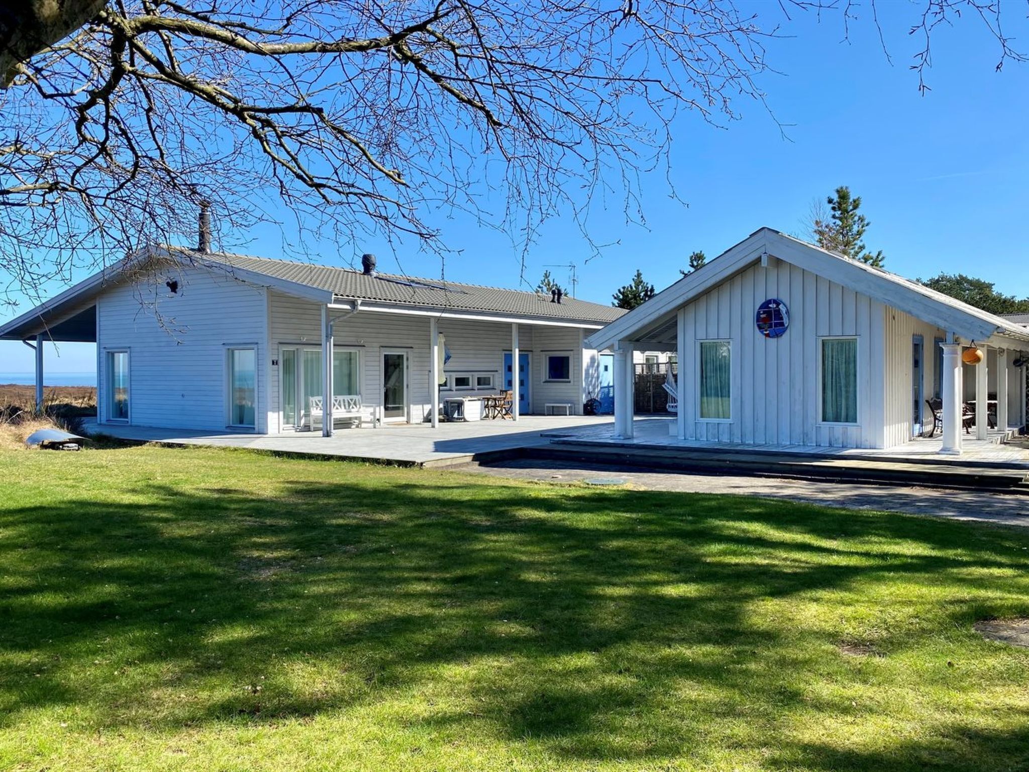 A white building with a covered porch and a small attached structure.