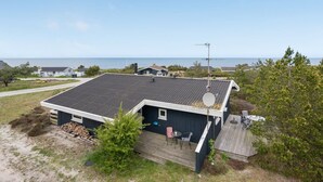 A two-story house with a dark roof, a satellite dish, and a deck with outdoor furniture.