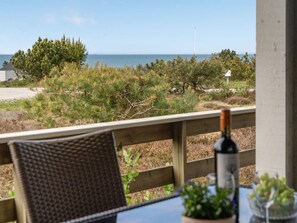 A wooden deck with a table and chairs, overlooking a beach with sparse vegetation and a clear view of the ocean. - "Arun" - 150m from the sea by Interhome (Læsø)