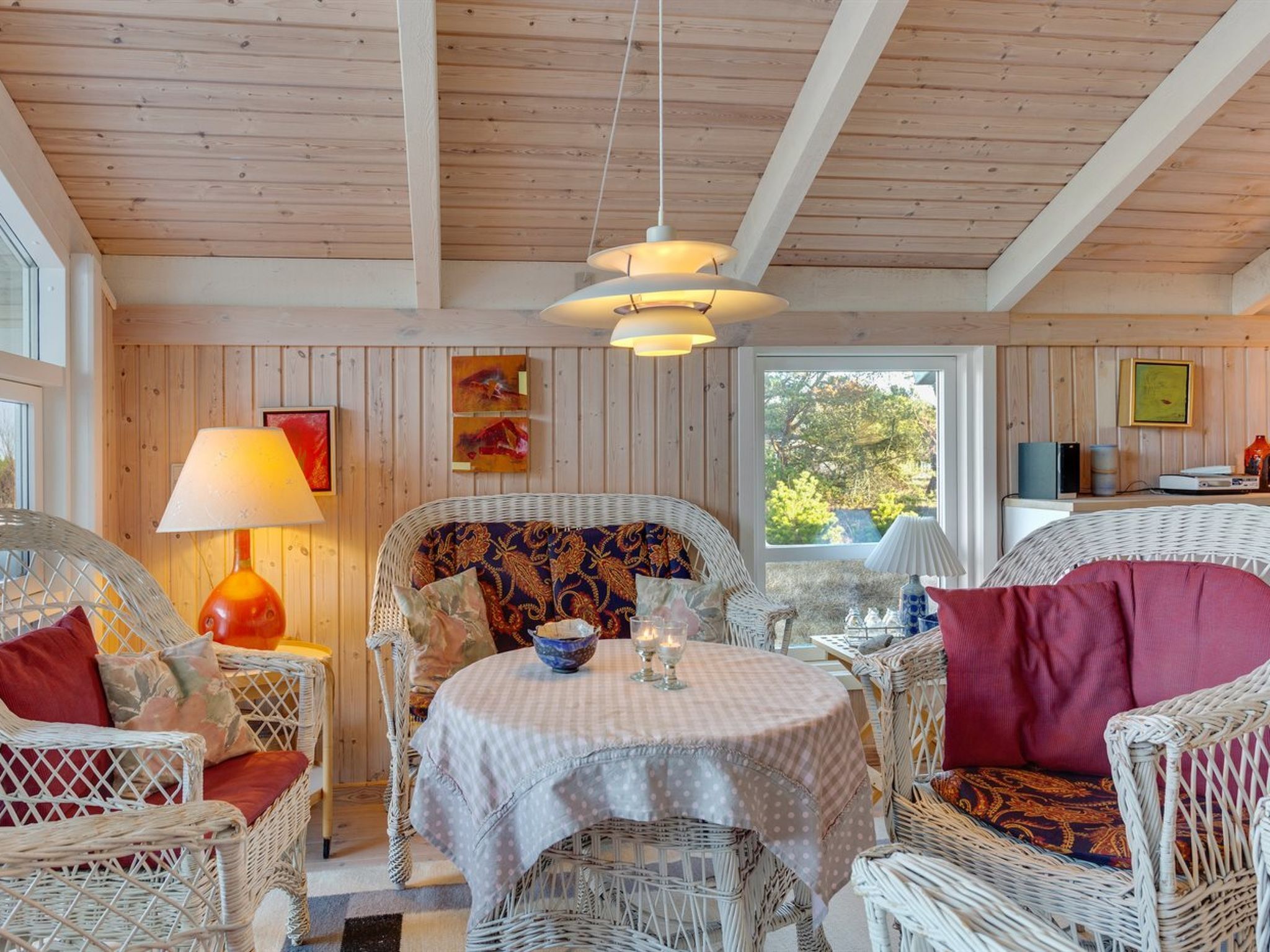 Una habitación acogedora con muebles de mimbre, una mesa redonda y un techo con vigas de madera.