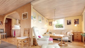 Ein gemütliches, gut beleuchtetes Zimmer mit Holzböden, einer Couch, einem Esstisch und einem Stuhl.