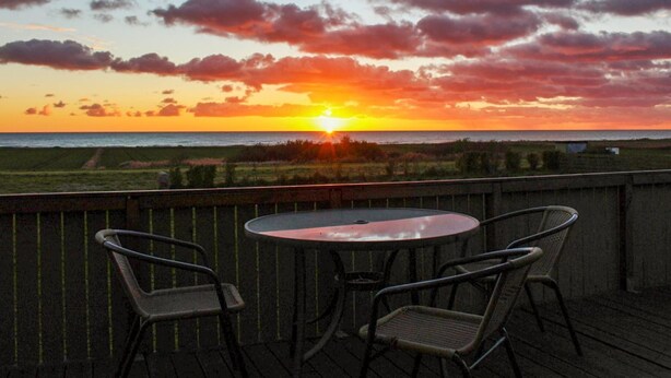 Ein Sonnenuntergangsblick von einem Balkon mit zwei Stühlen und einem Tisch.