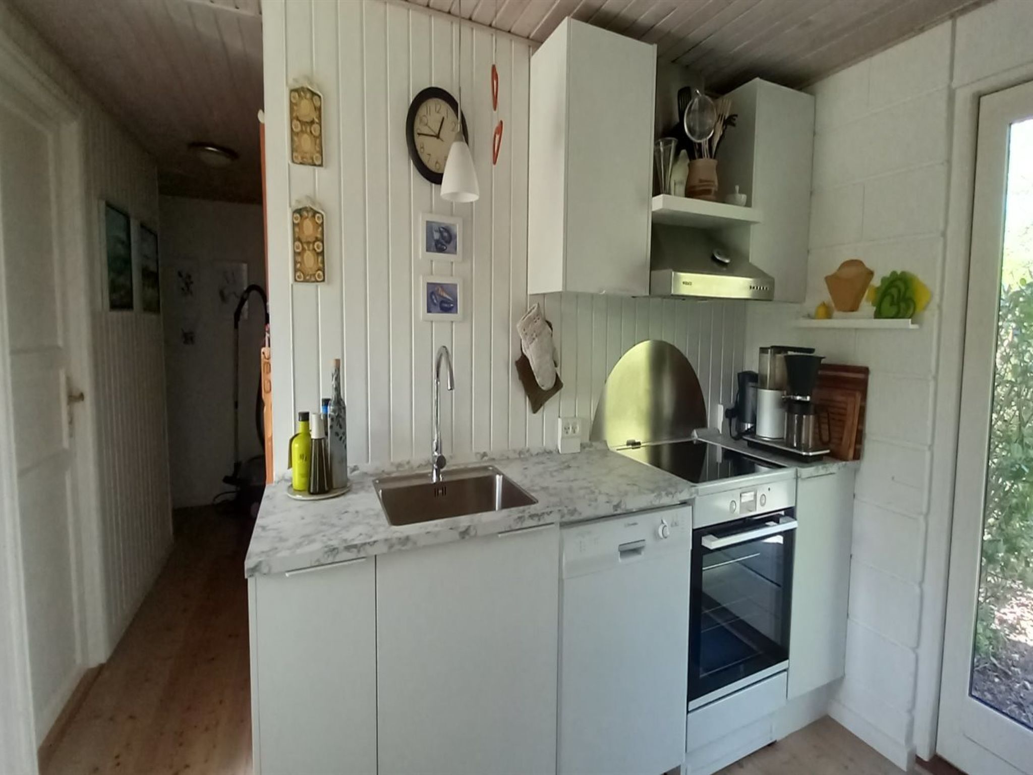 A kitchen with white cabinets, a sink, a stove, and a window.