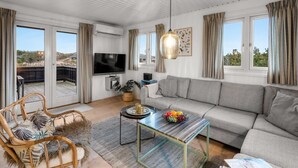 A modern living room with a sofa, television, and a dining table with a fruit bowl. - "Iken" - 500m from the sea by Interhome (Ringkøbing)