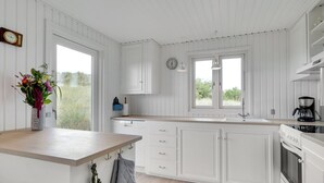 A kitchen with white cabinetry, a wooden countertop, a sink, a stove, and a clock on the wall. - "Iken" - 500m from the sea by Interhome (Ringkøbing)