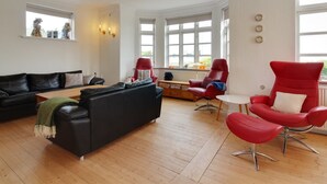 A modern living room with a black leather sofa, red chairs, and a wooden coffee table. - "Kosara" - 50m from the sea by Interhome (Frederikshavn)