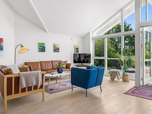 Een moderne woonkamer met een bank, fauteuils, een salontafel, een televisie en kunstwerken aan de wanden.